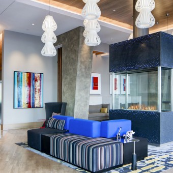 Inviting lobby with open seating, large-screen TVs, and a glass fireplace centerpiece.