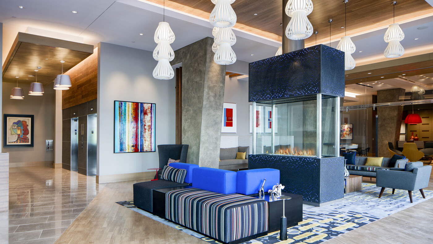 Inviting lobby with open seating, large-screen TVs, and a glass fireplace centerpiece. 
