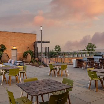 An expansive rooftop sun deck featuring sitting areas and tables for dining